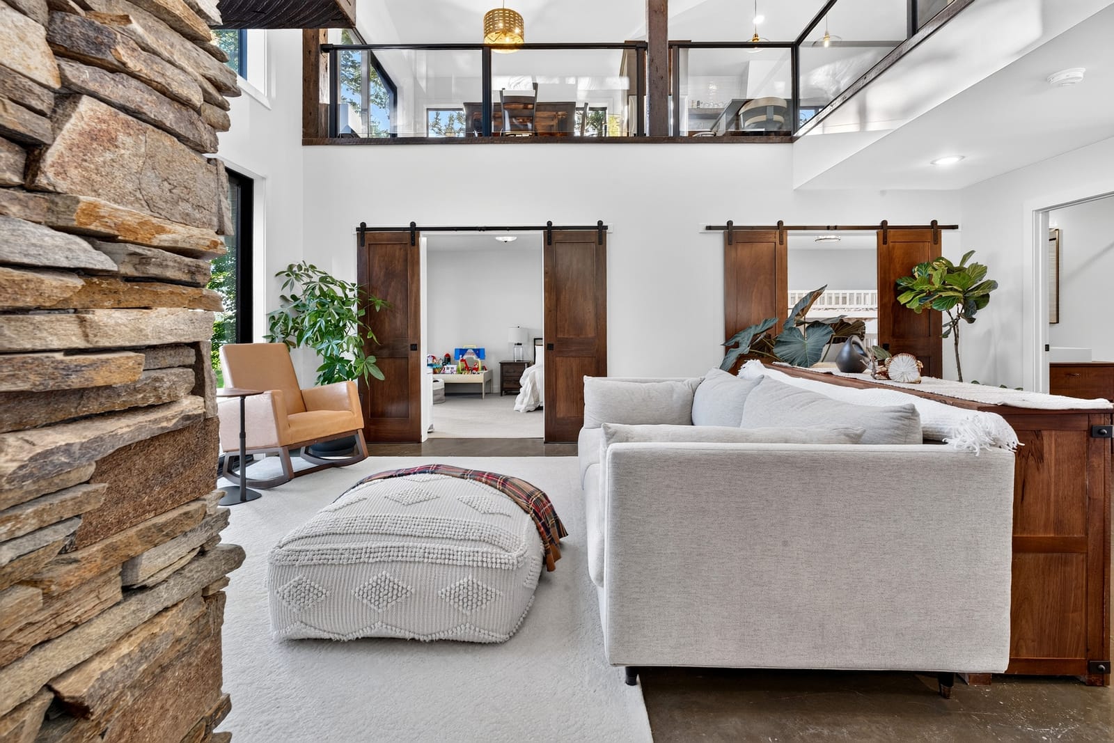 The great room under the loft, with sliding barn doors and the stone chimney.