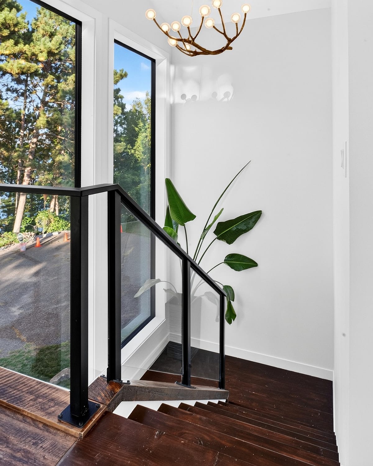 The stair, looking up through the volume past black-framed glass railings.