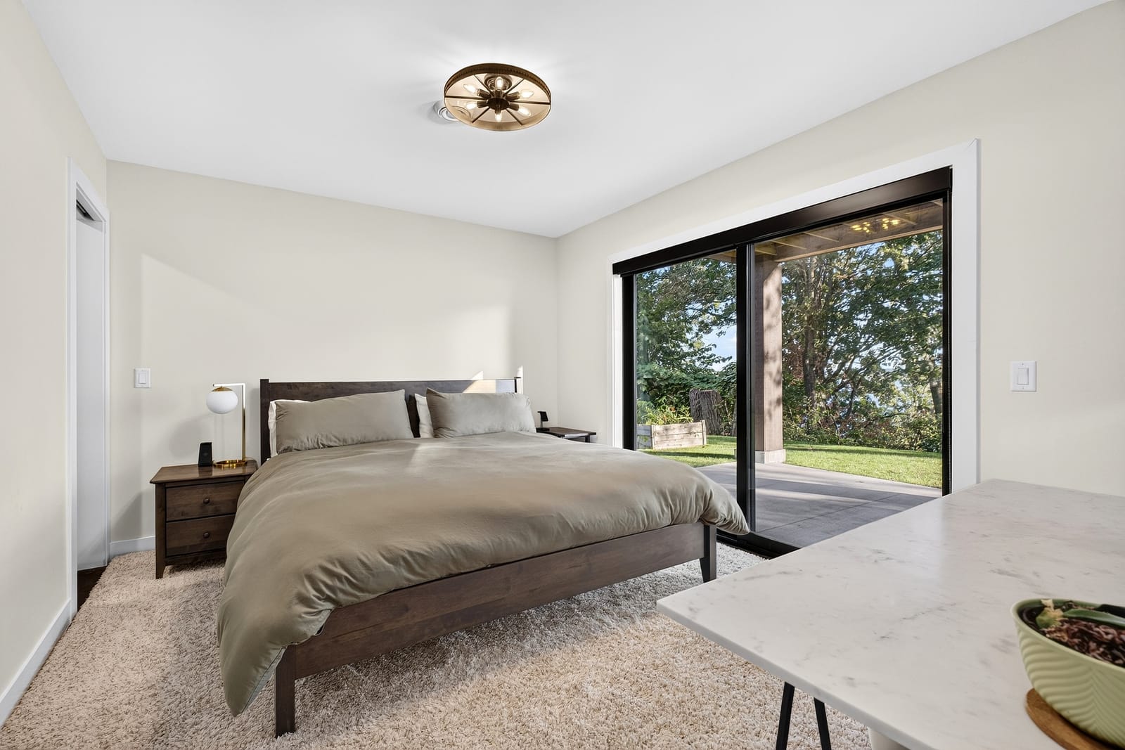 The second primary suite, opening to the lawn through its own sliding doors.